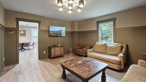 A spacious living room with a wooden coffee table, beige sofa, and a chandelier.
