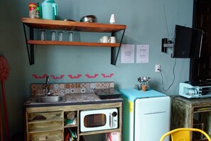 A compact kitchen with a microwave, toaster, and wooden shelves. - Estudio `Centro histórico  Morelia Michoacan` (Morelia)