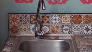 A kitchen with a sink, a decorative backsplash, and a wall with red text. - Estudio `Centro histórico  Morelia Michoacan` (Morelia)