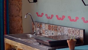 A compact kitchen with a sink, a microwave, and a small refrigerator. There are shelves above the sink and a decorative tile backsplash. - Estudio `Centro histórico  Morelia Michoacan` (Morelia)