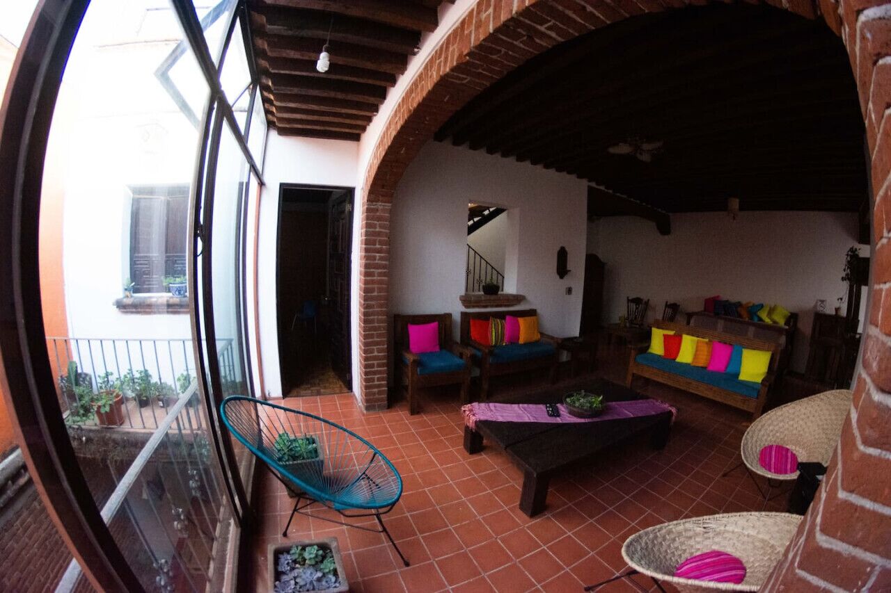 Un espace patio accueillant avec un banc en bois, une chaise en osier et un canapé agrémenté de coussins colorés.