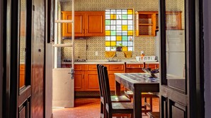 Une cuisine avec des meubles de rangement en bois, un pare-feu en carreaux et une fenêtre à motifs géométriques.