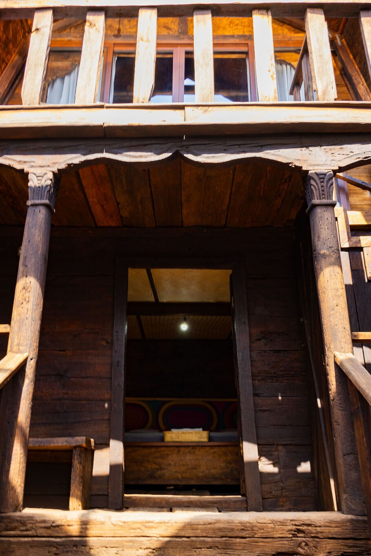 A wooden staircase leading to a room with a bed and a window.