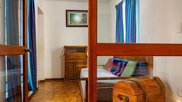 Quarto com cama de madeira, cómoda, mesinha e um quadro pendurado na parede.