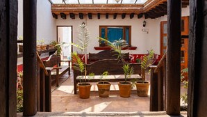 A covered patio area with wooden benches and potted plants. - Troje tradicional purépecha - live the experince (Morelia)
