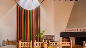 A dining area with a table set for two, a potted plant, and a fireplace. - Troje tradicional purépecha - live the experince (Morelia)