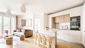 A modern kitchen with white cabinets, a central island, and a built-in oven. - Appart. Victoria(sleeps 7, 2 parking spaces)- Les Demoiselles à Versailles (Versailles)