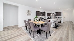 A modern apartment with a dining area, kitchen, and a separate bar area. - Freshly Built 4BR, 2.5-Bath Home in North Houston (Houston)
