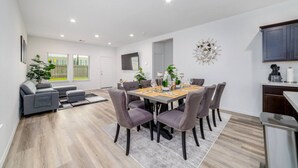 A modern dining area with a rectangular table, six chairs, and a grey sofa. - Freshly Built 4BR, 2.5-Bath Home in North Houston (Houston)