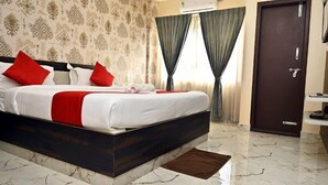Habitación de hotel con una cama grande, piso de mármol, cabecera de madera oscura y una puerta con manija.