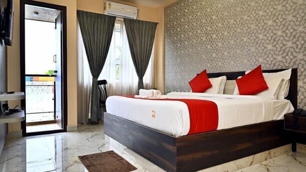 Habitación de hotel con cama, televisión, balcón y aire acondicionado.