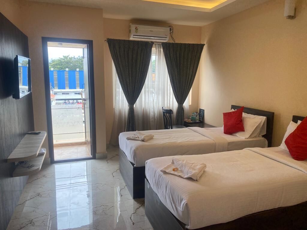 A hotel room with two beds, a TV, a desk, and a view of the outside.