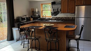 A modern kitchen with a central island, bar stools, a built-in oven, and a large window. - Waterfall View from Secluded 4 Bed Cabin in East Branch, NY with Mountain Views (East Branch)