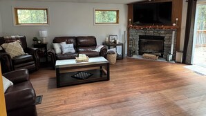 A spacious living room with a fireplace, leather sofas, and a coffee table. - Waterfall View from Secluded 4 Bed Cabin in East Branch, NY with Mountain Views (East Branch)