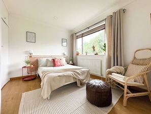 Une chambre à coucher avec un lit, une chaise, une fenêtre et un radiateur.