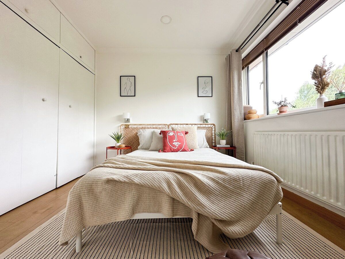 A bedroom with a bed, bedside tables, a window, and a radiator.