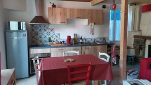 A compact kitchen with a refrigerator, wooden cabinets, and a dining table with chairs.