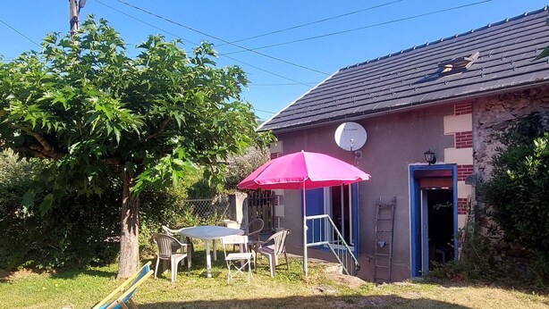 A backyard with a table and chairs, a swing set, and a building with a satellite dish.