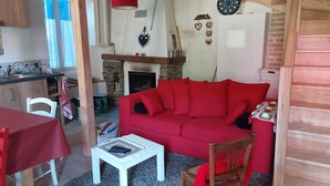 A cozy living room with a red sofa, a small white table, and a fireplace.