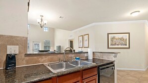 A modern kitchen with granite countertops, stainless steel appliances, and wooden cabinetry. - Bella Piazza Resort 3BR Charming Condo, By Disney (Davenport)