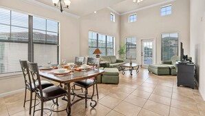 A spacious living area with a dining table set for four, a sofa, and a coffee table. - Bella Piazza Resort 3BR Charming Condo, By Disney (Davenport)