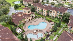 A residential complex with a central swimming pool, multiple buildings with similar architecture, and well-maintained landscaping. - Bella Piazza Resort 3BR Charming Condo, By Disney (Davenport)