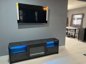 Relax in this stylish living room with a flat-screen TV, shelf, and dining area.
