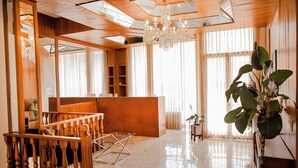 A spacious hotel lobby with a wooden reception desk, a chandelier, and large windows allowing natural light. - Violeta Hotel Boutique (Tepatitlan de Morelos)