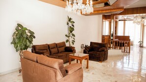 A spacious living area with a brown sofa set, a wooden coffee table, and a chandelier. - Violeta Hotel Boutique (Tepatitlan de Morelos)