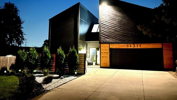 A modern two-story house with a garage, a well-maintained garden, and a clear sky. - Marvelous Modern Spacious 4-bedroom house  near interstate and Top Golf.  (Omaha)