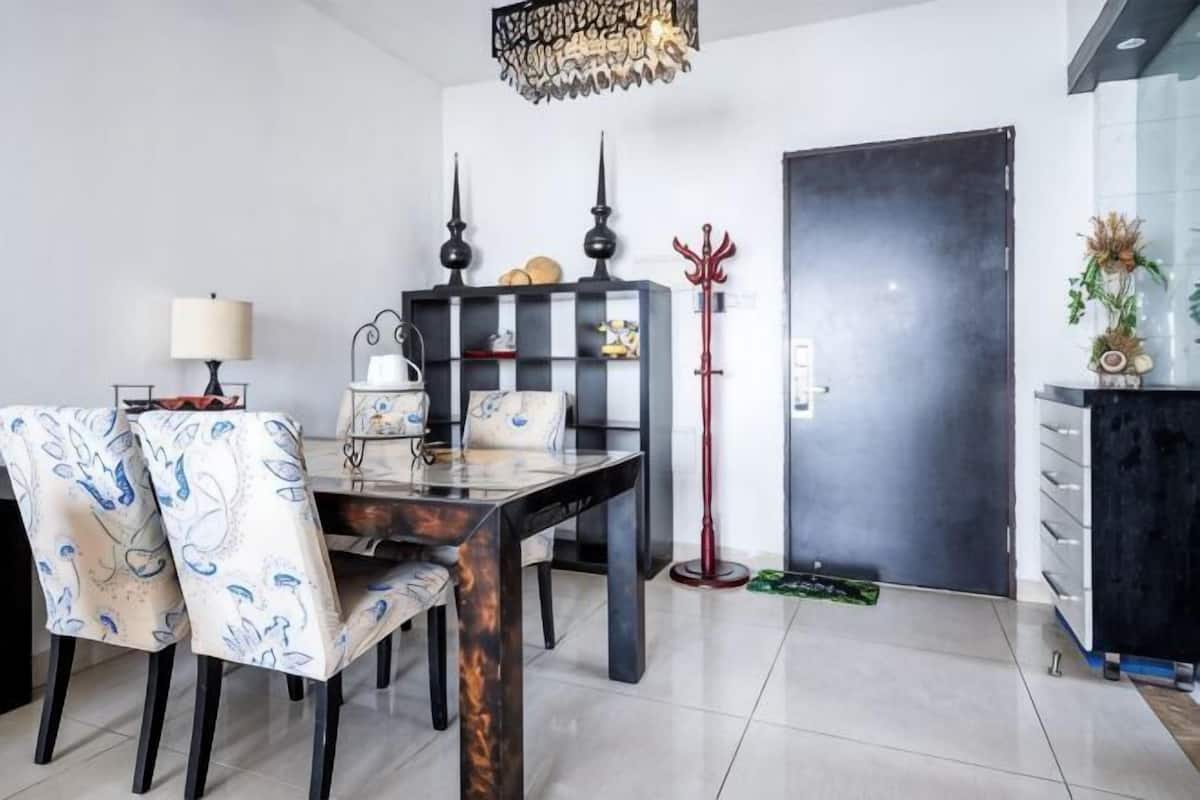 A dining area with a table and chairs, a bookshelf, a coat rack, and a door.