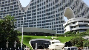A modern hotel with a distinctive curved facade and a large central entrance. - Beihai Tuyu Oceanfront Scenic Apartment (Beihai)