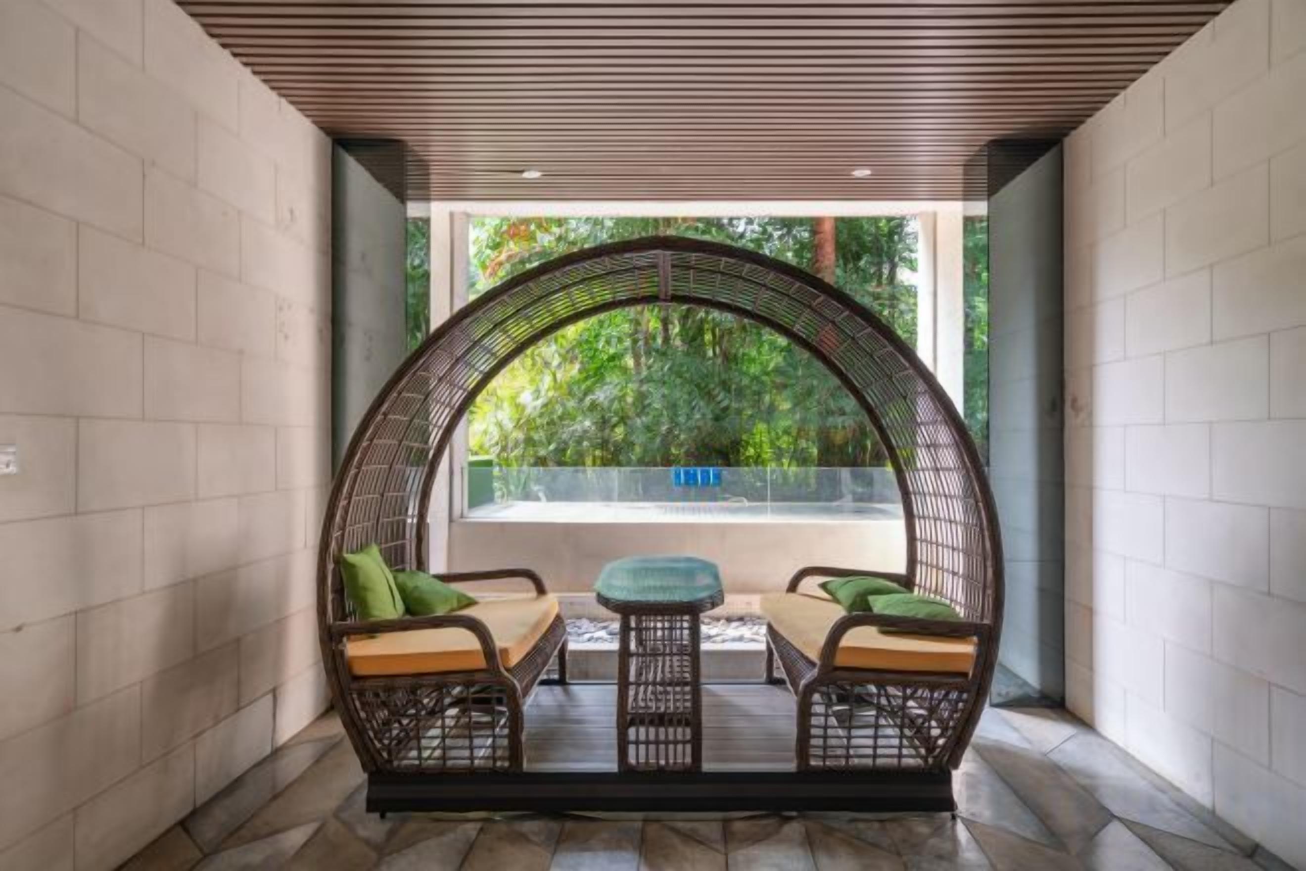 A seating area with a curved wooden ceiling, a view of greenery outside, and a glass barrier.