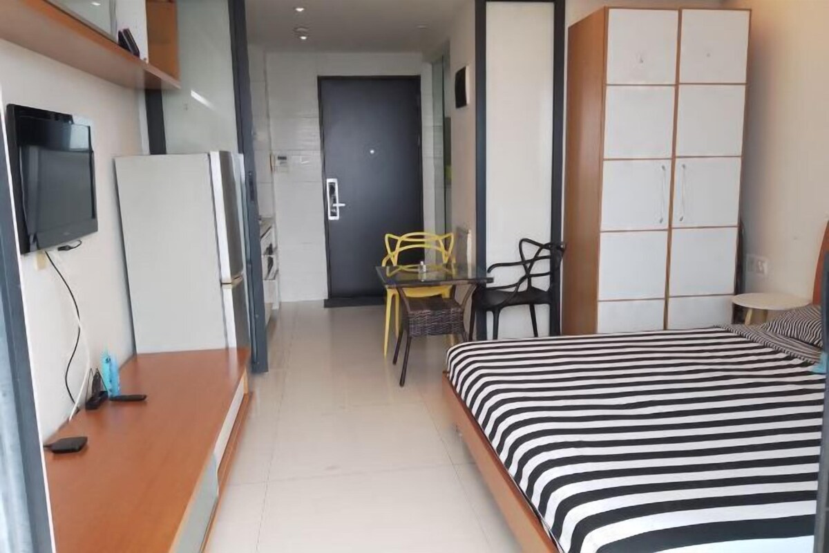Ein Hotelzimmer mit einem Bett, einem Schreibtisch, einem Stuhl, einem Fernseher und einem Kleiderschrank.