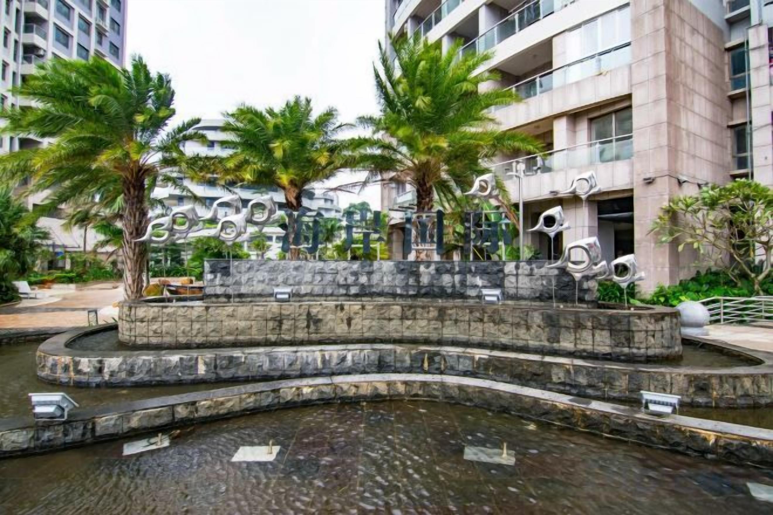 A water feature with palm trees and decorative sculptures in an urban setting.