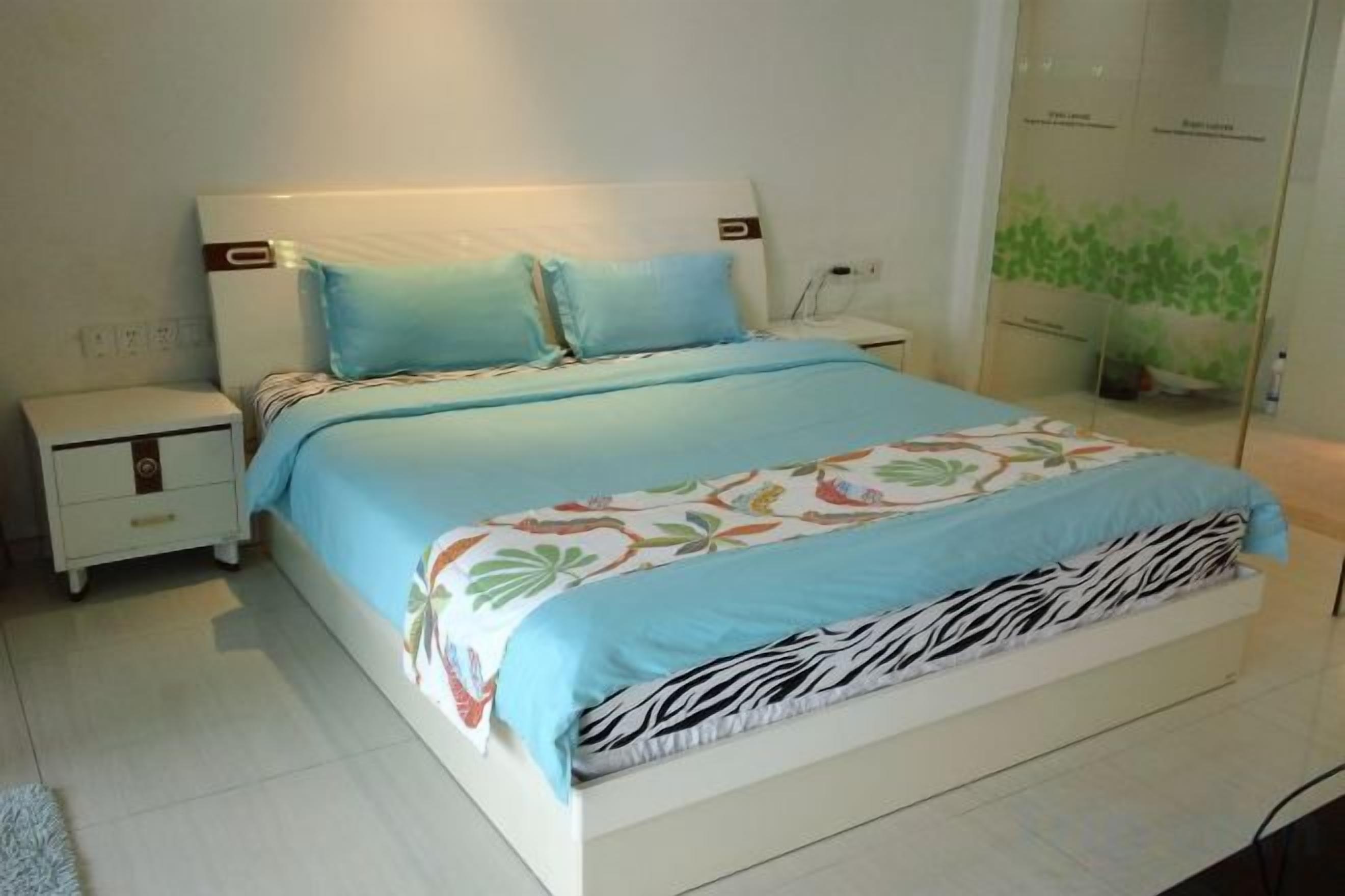 Una cama con cubrecama estampado de cebra, una mesita de noche y una planta fijada a la pared.
