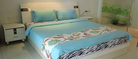 Una cama con cubrecama estampado de cebra, una mesita de noche y una planta fijada a la pared.
