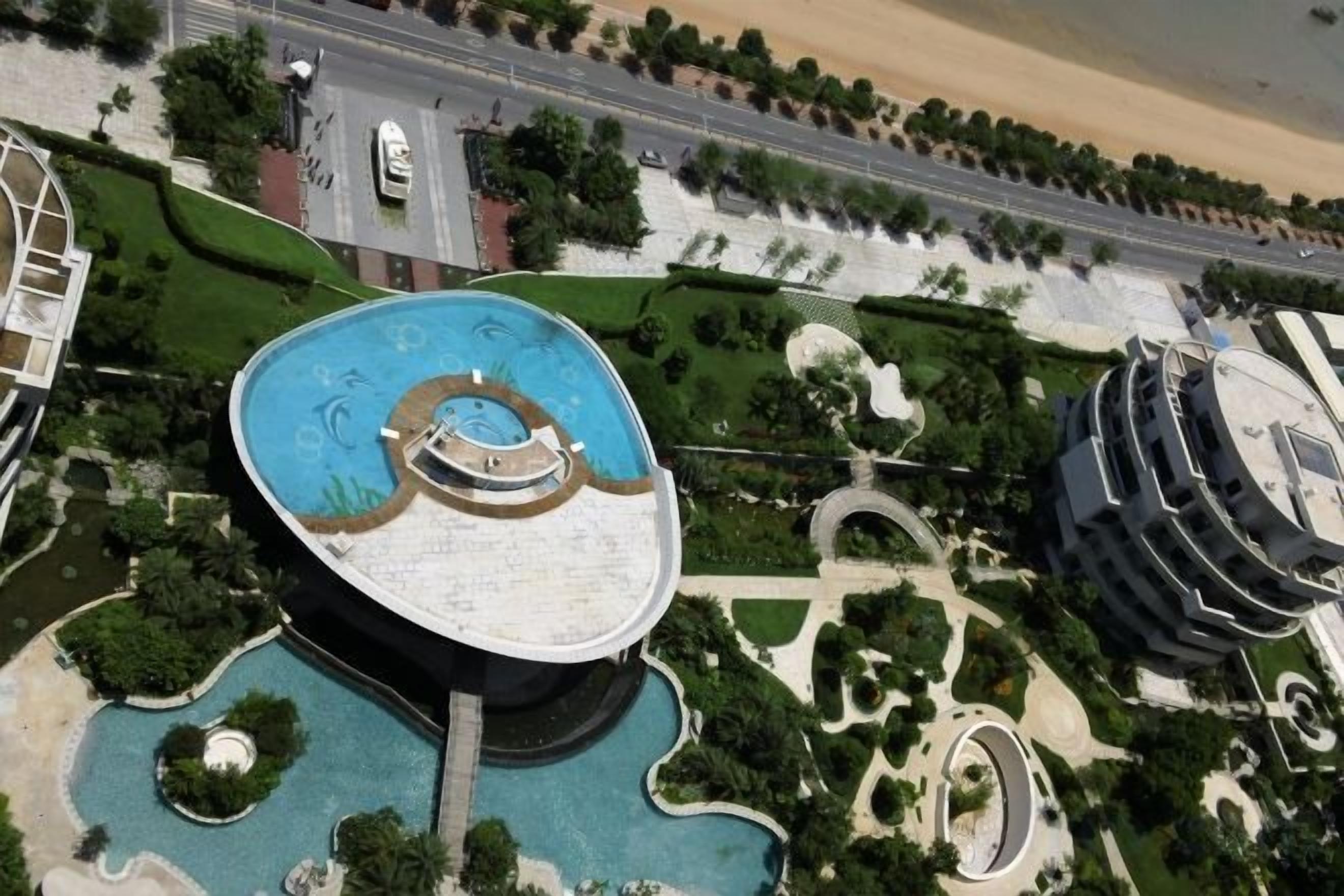 A large building with a circular central courtyard, surrounded by landscaped areas and a road.