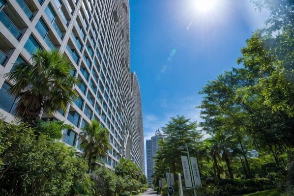 Un edificio alto con fachada de entramado, rodeado de abundante vegetación y palmeras.