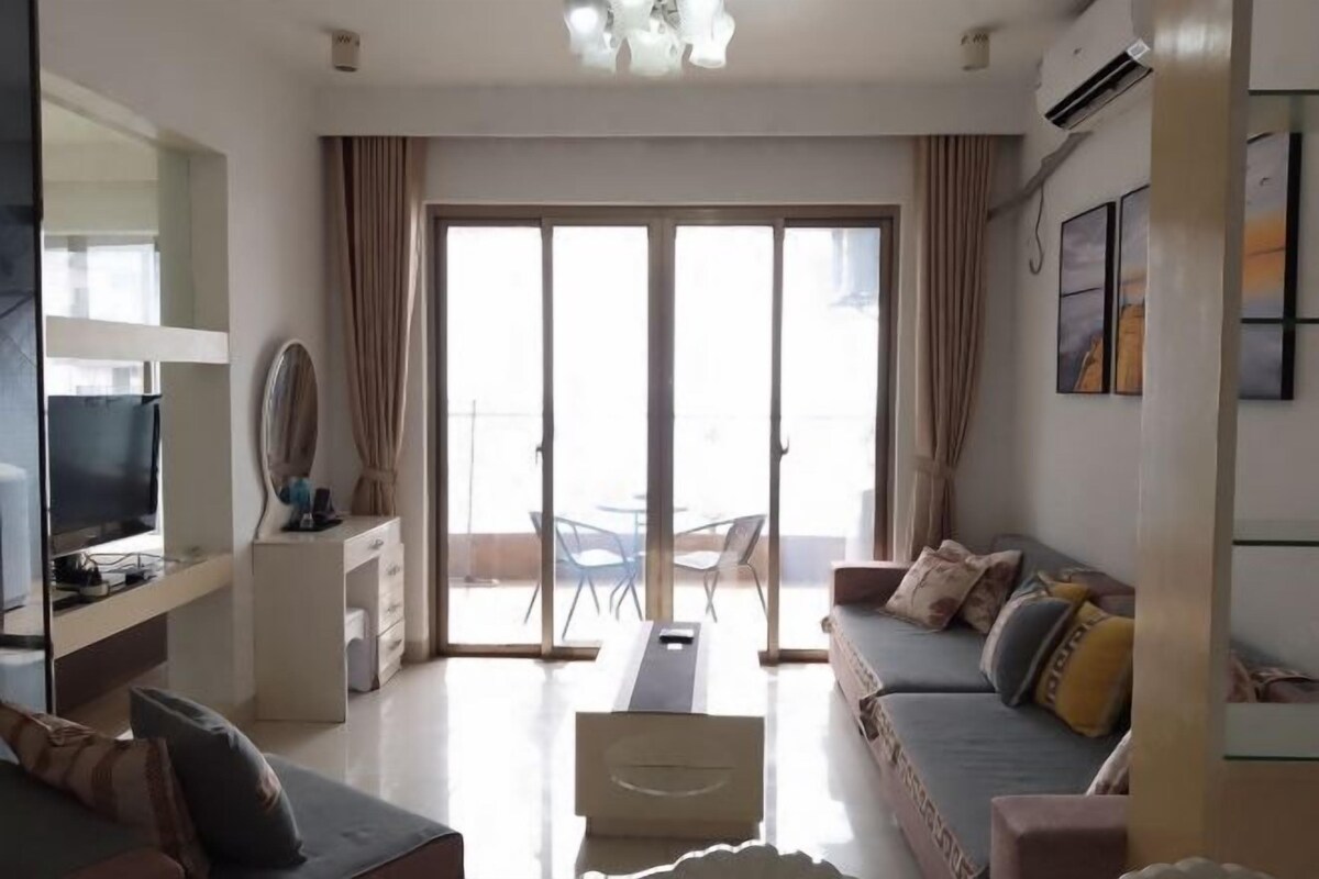 A modern living room with a sofa, television, and a dining area with chairs.