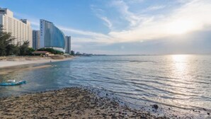 A coastal hotel with a beachfront view, a sandy beach, and a body of water. - Beihai Tuyu Oceanfront Scenic Apartment (Beihai)