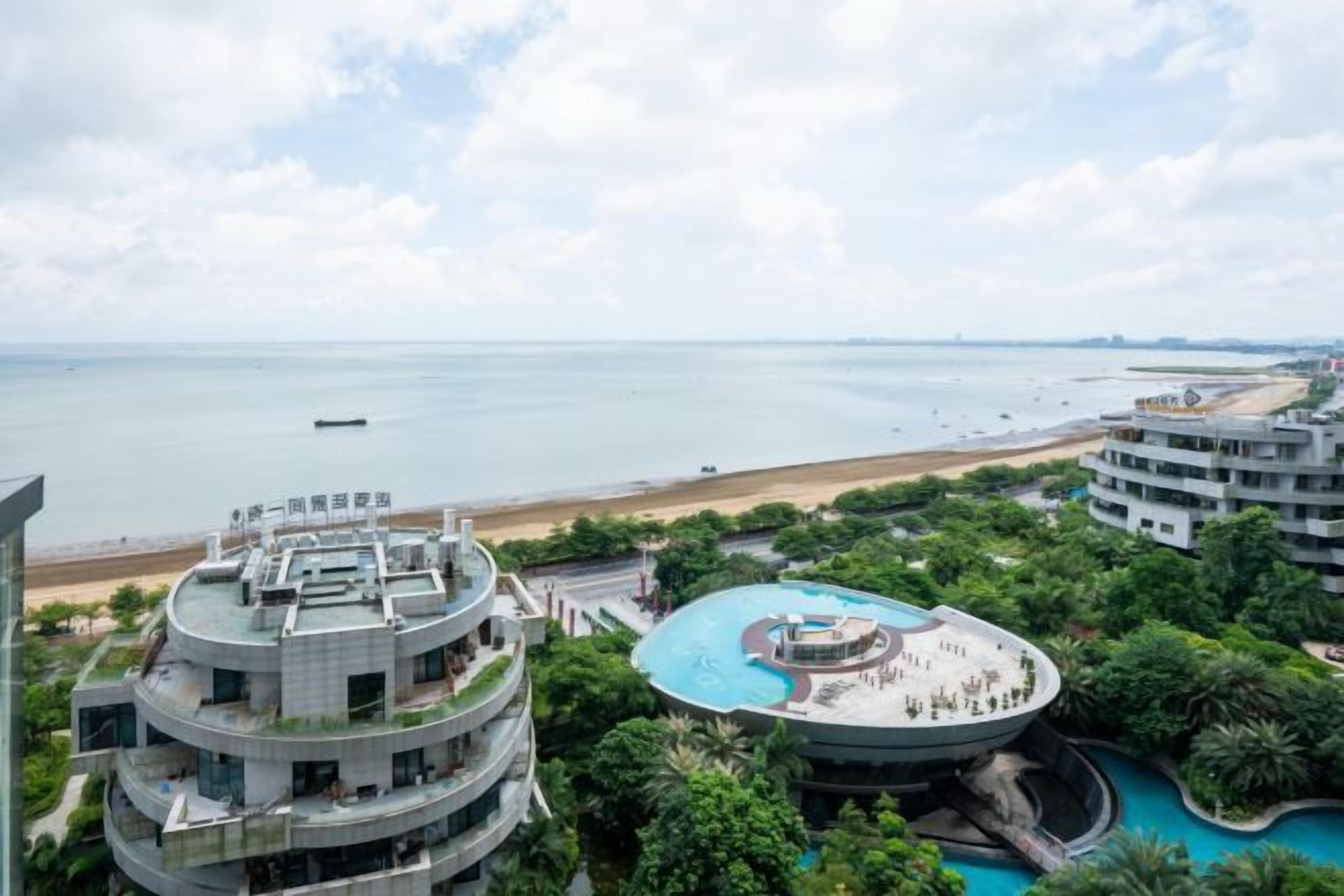 A high-rise hotel with a rooftop pool and a view of the beach.