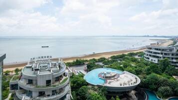 A high-rise hotel with a rooftop pool and a view of the beach.