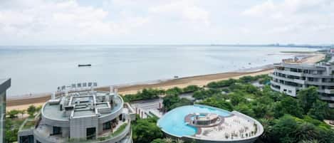 A high-rise hotel with a rooftop pool and a view of the beach.