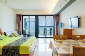 Ein Hotelzimmer mit Bett, Esstisch, Fernseher und Balkon mit Blick.
