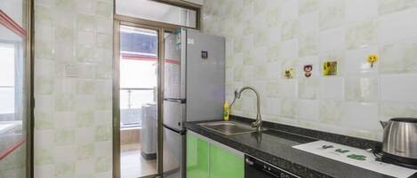 A kitchen with green cabinets, a stainless steel refrigerator, a sink, and a dishwasher.