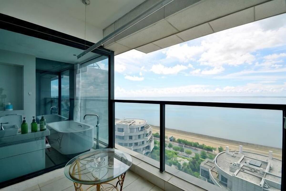 A modern bathroom with a glass-enclosed shower, a bathtub, and a glass table.