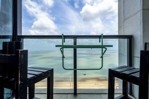 Ein Balkon mit Meerblick, einem Metallgestell und zwei Holzstühlen.
