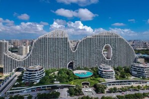 Un hotel moderno con una arquitectura distintiva en forma de ola, varios balcones y un patio central.