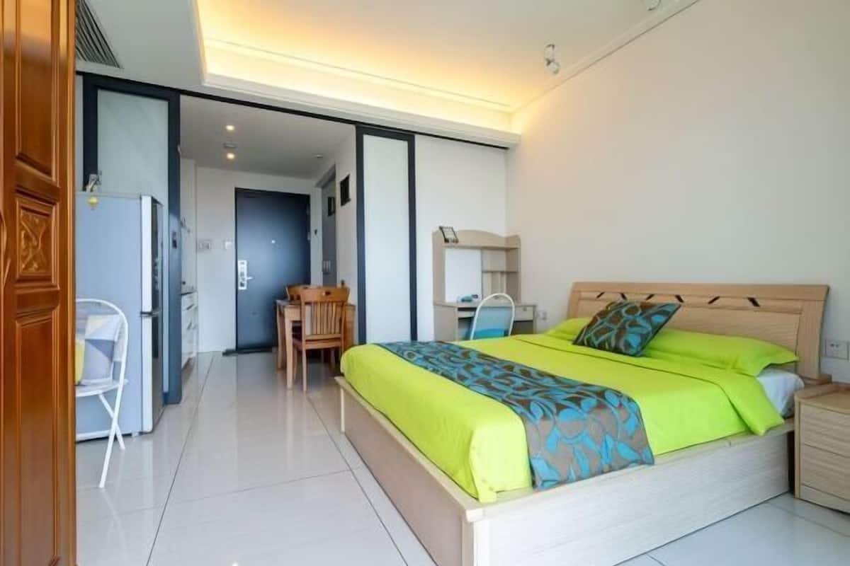 A modern hotel room with a large bed, a desk, and a chair.
